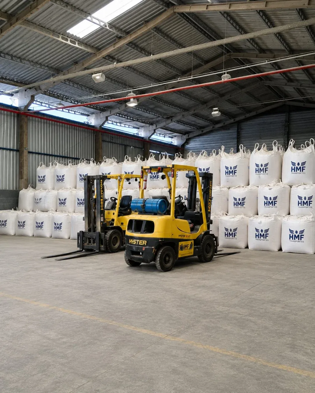 Big bags com a marca HMF e empilhadeiras no galpão